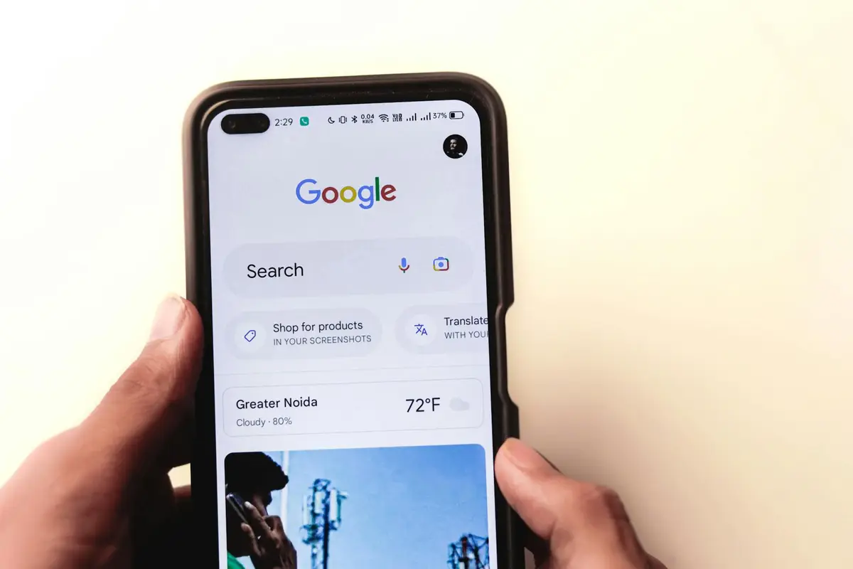 يد تحمل هاتفًا ذكيًا مع تطبيق بحث جوجل لاستخدام AI Mode بالعربية