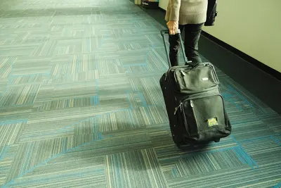 مسافر يحمل حقيبته في صالة مطار مع AirTag لتتبع الأمتعة في رحلة السفر والحج
