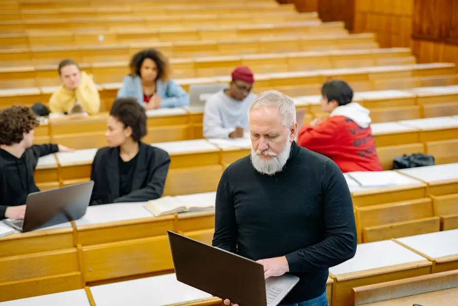 أستاذ جامعي مع طلاب على أجهزة لابتوب في قاعة محاضرات