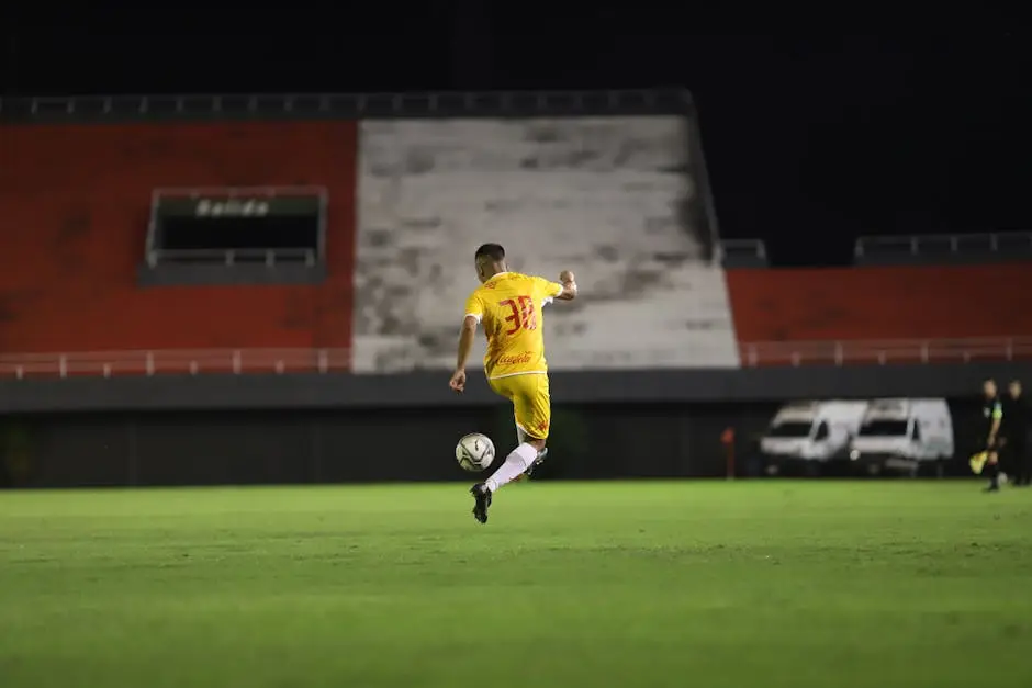 لاعب كرة قدم يسدد الكرة في مباراة ليلية تحت أضواء الملعب - أجواء TOTS