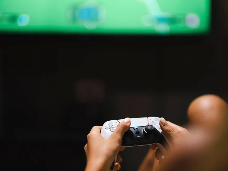 يدان تمسكان بذراع تحكم بلايستيشن أثناء اللعب بمنتخب السعودية في EA Sports FC 26