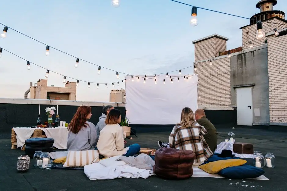 بروجكتر منزلي صغير محمول لليلة سينما على السطح مع أضواء وأصدقاء