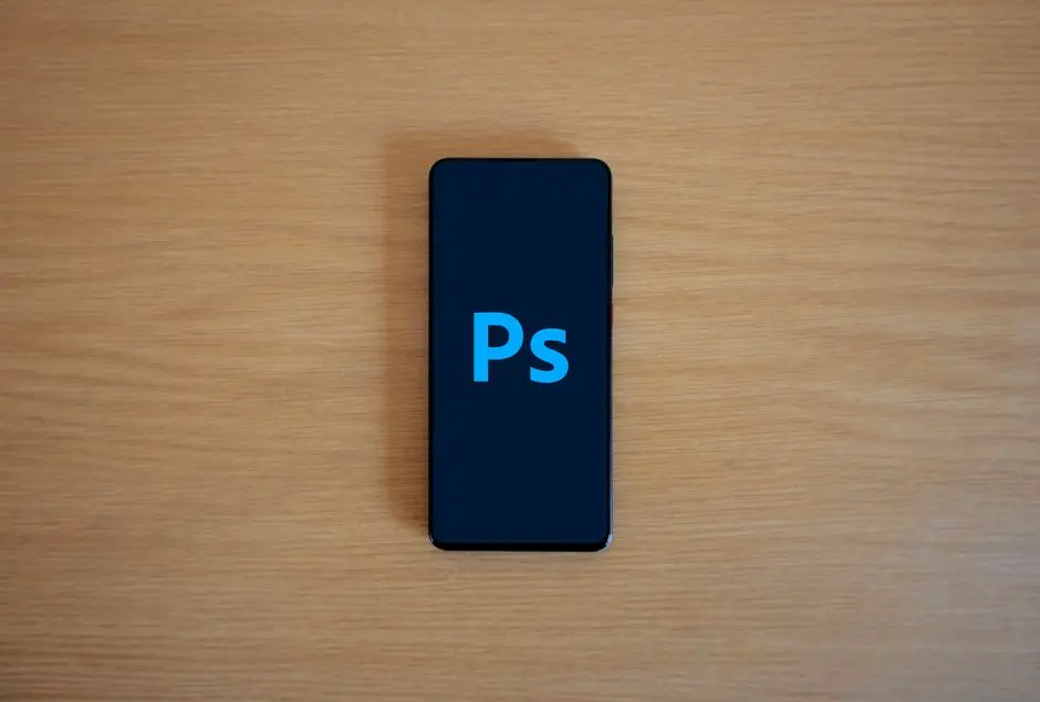 منظر علوي لآيفون يعرض Adobe Photoshop على سطح خشبي - تطبيق Darkroom للأيفون