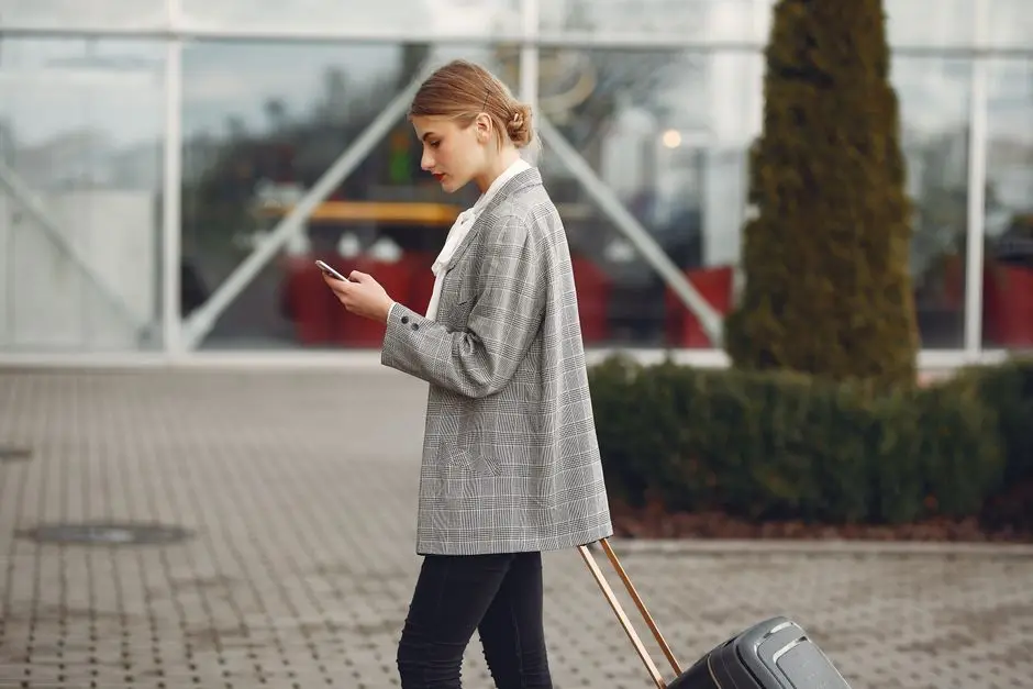 مسافرة تحمل حقيبة سفر وتستخدم جوالها في الشارع - تطبيق Airalo لتفعيل eSIM قبل الوجهة