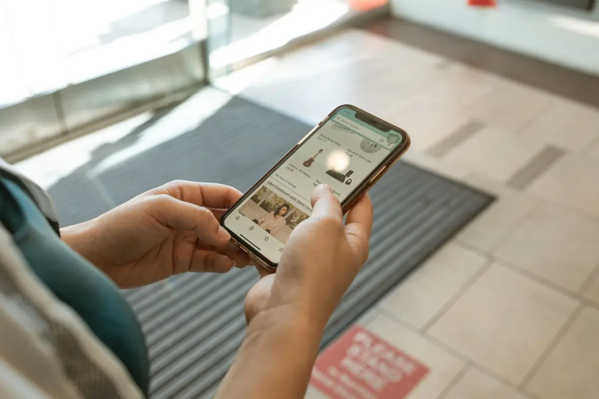 يد تضغط على تطبيق Apple Store لإتمام الطلب المسبق لـ ايفون Duo