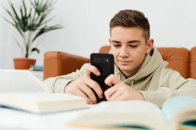 مراهق يستخدم شات جي بي تي للمراهقين عبر هاتفه الذكي خلال المذاكرة