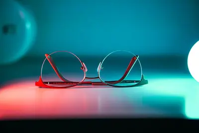 نظارات ميتا ذكية بإضاءة نيون على سطح عاكس تعرض تصميم Ray-Ban Meta